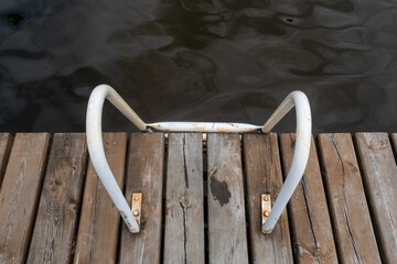 Wooden pier with metal ladder leading into dark water
