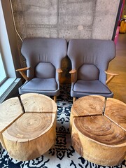 Modern Lounge Area: Two comfortable armchairs and wooden side tables against a concrete wall.