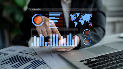 A business professional engages with interactive data visualizations on a digital dashboard while working on performance metrics in a modern office environment. Impute