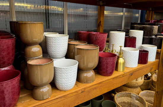 Different empty ceramic flower pots on wooden shelf at a gardening shop