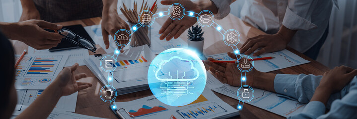 Team members engage in a collaborative meeting showcasing hands reaching for cloud technology, with data visuals highlighting progress and innovation in a modern office setting. Trope