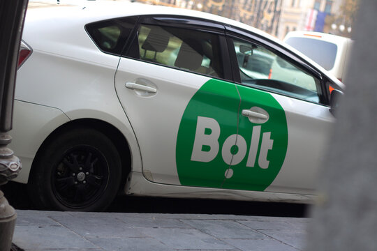 Tbilisi, Georgia - November 29, 2025: Horizontal street photo. Green Bolt taxi logo on door of white car on city parking. Concept of private transport, delivery, speed, mobile app, road trip, drive
