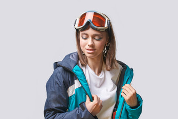 Female young caucasian skier preparing for winter sports in warm jacket and goggles.