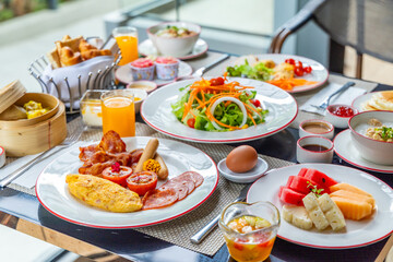 Delicious continental breakfast spread with eggs, bacon, fresh fruits, and salad on dining table. Bright and inviting morning meal set in modern restaurant setting.