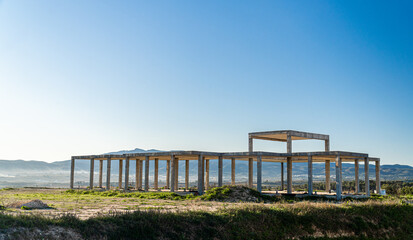 Abandoned construction building isolated on a field at sunset.