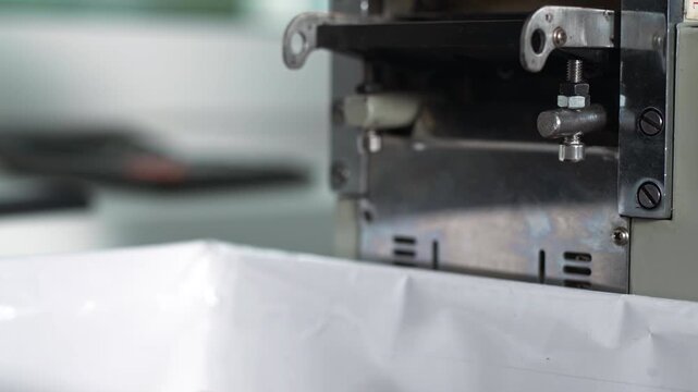 Industrial blade press cutting layers of black technical fabric in close view
