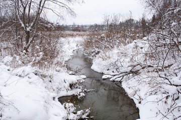 Winter snowy landscape with a river in the middle and trees