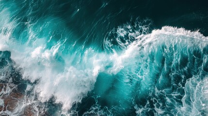 Fototapeta premium Aerial View of Turquoise Ocean Waves Crashing Against the Shoreline Under Bright Blue Sky in a Serene Coastal Landscape