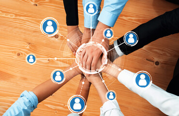 A dynamic image showing diverse hands coming together, symbolizing collaboration and networking, with digital icons representing connections on a wooden table background. Amity