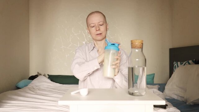 Young woman with cancer adding protein supplement to sports bottle, patient at home improving appetite and muscle mass, oncology diet, wellness, healthy drinks and fitness nutrition