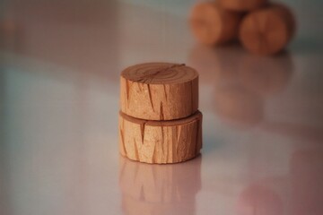 Wooden cylinders stacked on a reflective surface in soft light