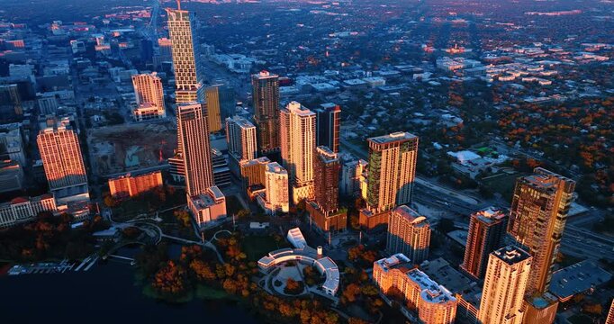 High-rises in the downtown of Austin, Texas, USA lit by the setting sun. Drone footage over the Colorado River at sunset.