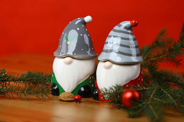 Close-up of ceramic Christmas gnome figurines with evergreen branches and small ornaments on a festive table.