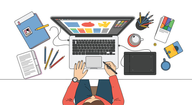 Top down view of a graphic designer or illustrator working on a laptop with a graphics tablet at a modern clean desk.