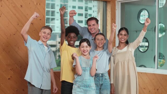 Smart teacher and diverse student standing while putting hand in the air to celebrate successful project.. Skilled instructor with high school children with mixed races in casual outfit . Edification - Powered by Adobe