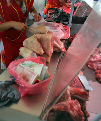 Butchers preparing fresh meat at a busy market during the day with colorful displays and lively atmosphere