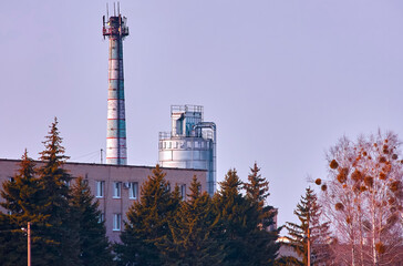 Factory with smokestack and industrial structure against a clear sky in an urban area