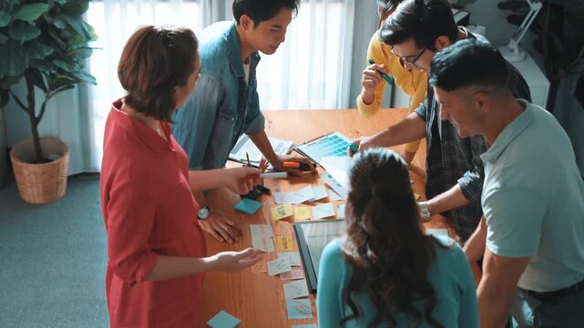 Top view of manager writing idea on sticky notes and explain idea about web design. Professional marketing team or programmer brainstorming idea while looking at tablet with color palette. Symposium. - Powered by Adobe