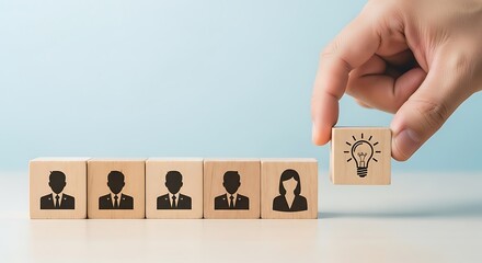 Hand placing wooden block with lightbulb idea icon next to row of business people silhouette blocks for selection
