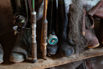 Vintage Fishing Equipment with Rods Reels and Waders in Rustic Storage