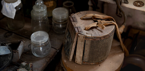 Vintage Cricket Cage Bait Container with Glass Jars on Rustic Wooden Table