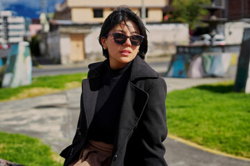 Obraz premium Stylish woman wearing sunglasses and black coat looking away