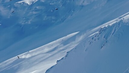 Slow motion aerial footage of a freeride skier carving through fresh powder snow on a steep alpine slope. Dynamic drone shot capturing the thrill of first tracks in pristine winter mountains. - Powered by Adobe