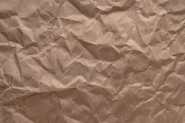Full-frame close-up of a crumpled and wrinkled brown kraft paper texture perfect for use as a seamless background or design element.