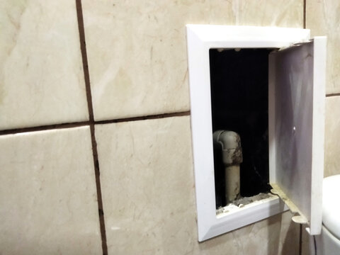 Unfinished wall opening reveals hidden plumbing in bathroom area