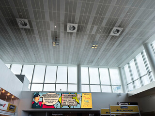 Fototapeta premium Bright Manchester airport terminal interior with large glass windows, banners, and security signage