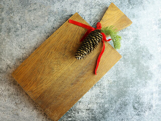 Rustic Wooden Board with Festive Pinecone and Red Ribbon. Vintage rustic wooden cutting board, Christmas decorations. Christmas menu background