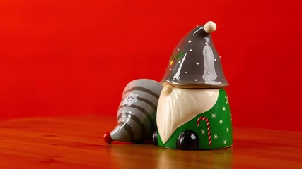 Green Christmas gnome figurine slowly rotating on turntable with tilted hat isolated on red background - Powered by Adobe