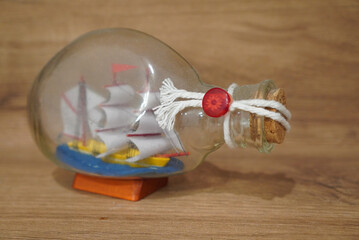 Miniature sailboat inside a glass bottle on a wooden surface