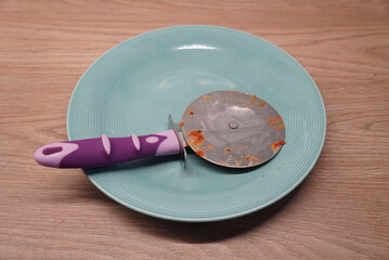 Pizza cutter on a teal plate, ready for slicing a delicious homemade pizza