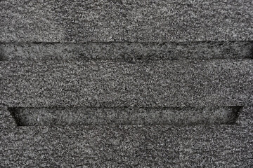 A close-up, horizontal image shows a heavily textured, dark gray foam surface with two pronounced horizontal grooves cut across it