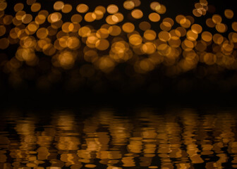Beautiful blurred gold yellow bokeh from ornamental lights flickering with reflection on water ripple effect. Background for celebrate party, merry Xmas, happy new year concept.