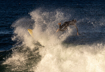 A surfer wearing a wetsuit wiping out on the lip of a wave