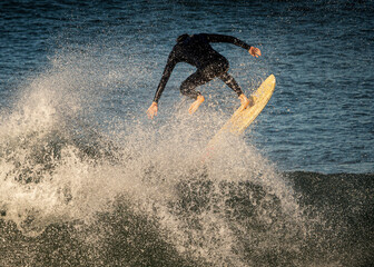 A surfer wearing a wetsuit launching off the lip of a wave