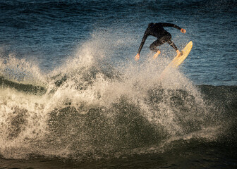 Fototapeta premium A surfer wearing a wetsuit launching off the lip of a wave