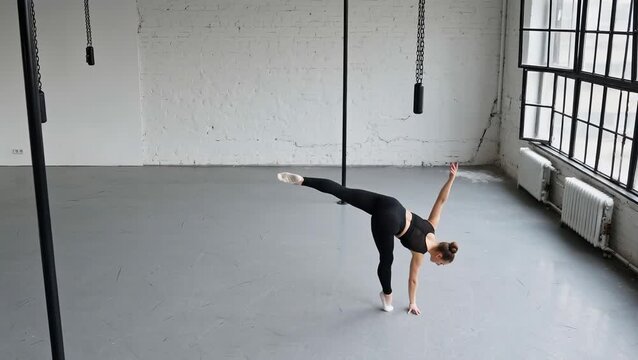 Female Dancer Performing Graceful Pose in Studio Space with Poles