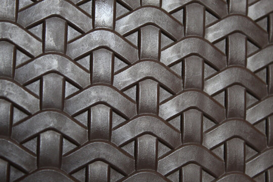 a textured surface featuring a woven pattern. The surface appears to be made of a dark, rubber-like material.