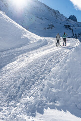 A couple skinning up a pisted track in Le Tour skiresort in the French Alps.