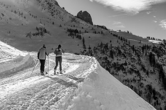 A couple skinning up a pisted track in Le Tour skiresort in the French Alps. In black and white.