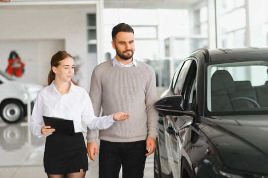 Salesperson consulting customer choosing car in showroom - Powered by Adobe