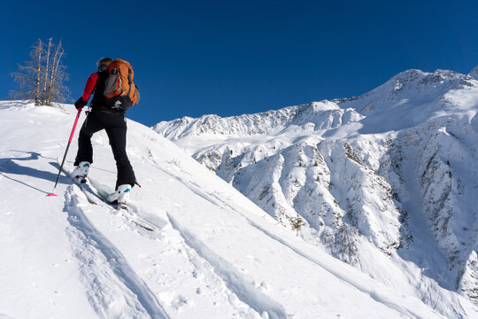 A woman pushing uphill in snowy terrain while skitouring in the French Alps. - Powered by Adobe