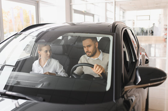 Couple test driving car in automobile dealership showroom