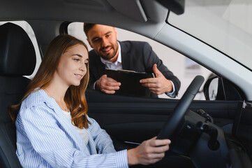 Woman test driving car discussing features with salesperson