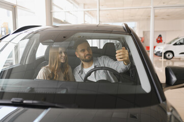 Happy couple taking selfie inside new car