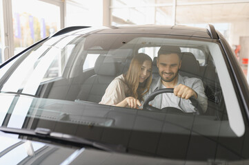 Young couple buying new car discovering features at dealership