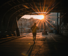 man running below a bridge in the city